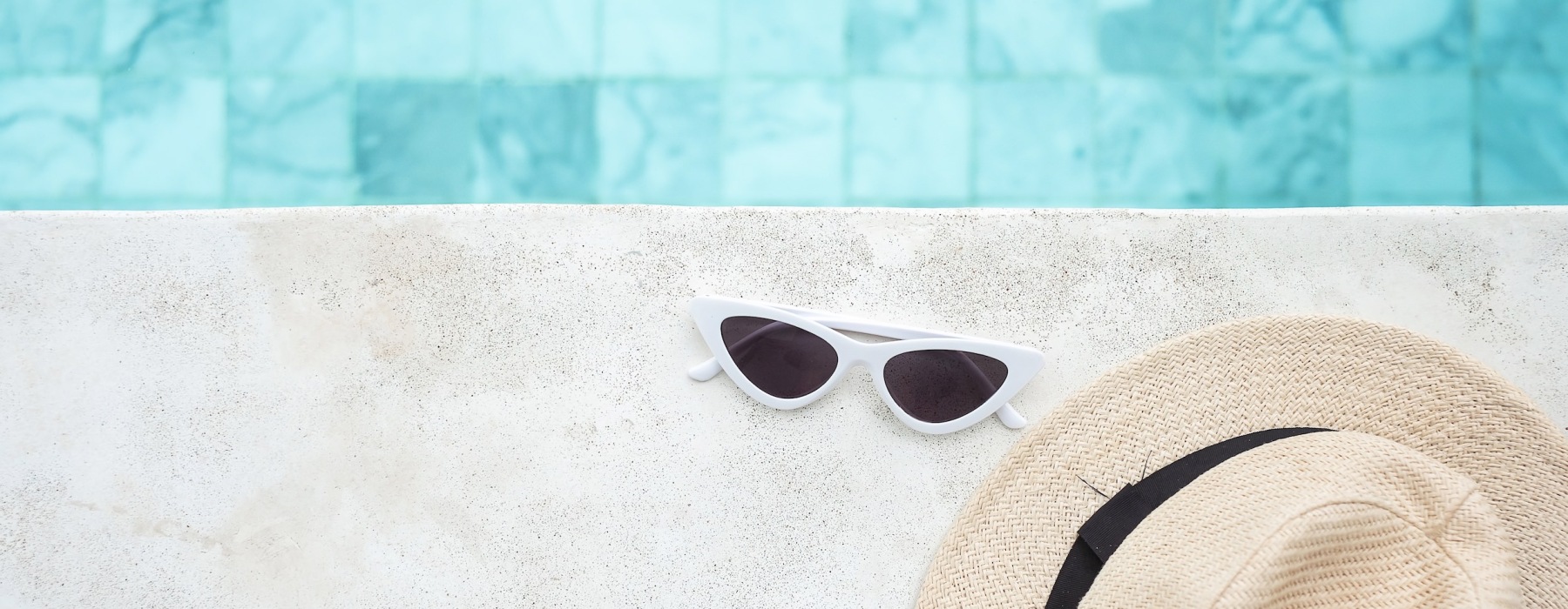 sunglasses and hat next to pool